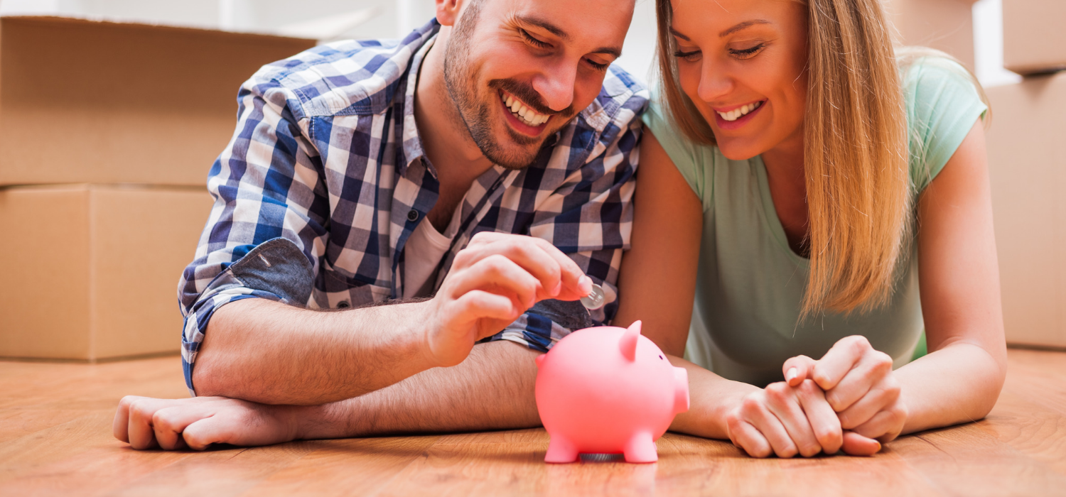 young couple putting money in the piggy bank