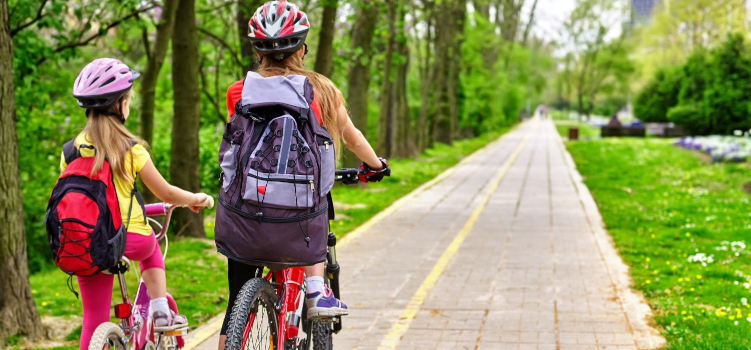 Mother and daughter riding bike on sidewalk