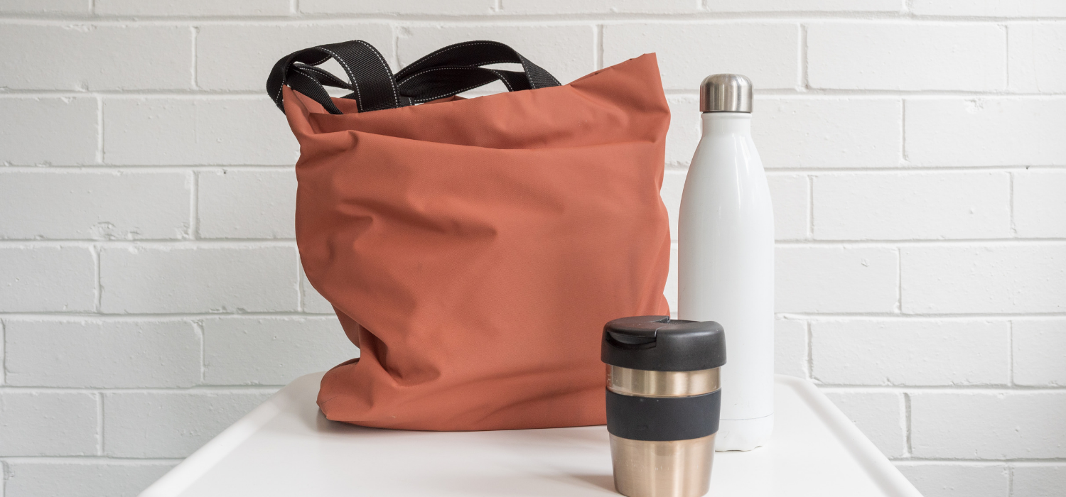 reusable plastic free bag, coffee mug, and water bottle on the kitchen counter